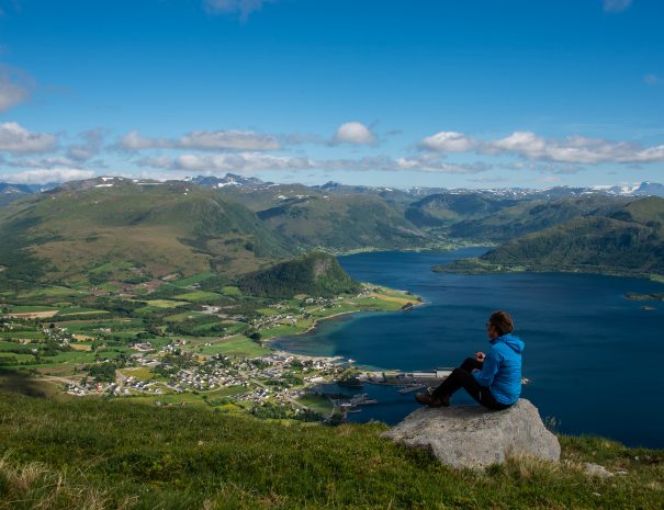 person sitting on rock looking out towards the fjords